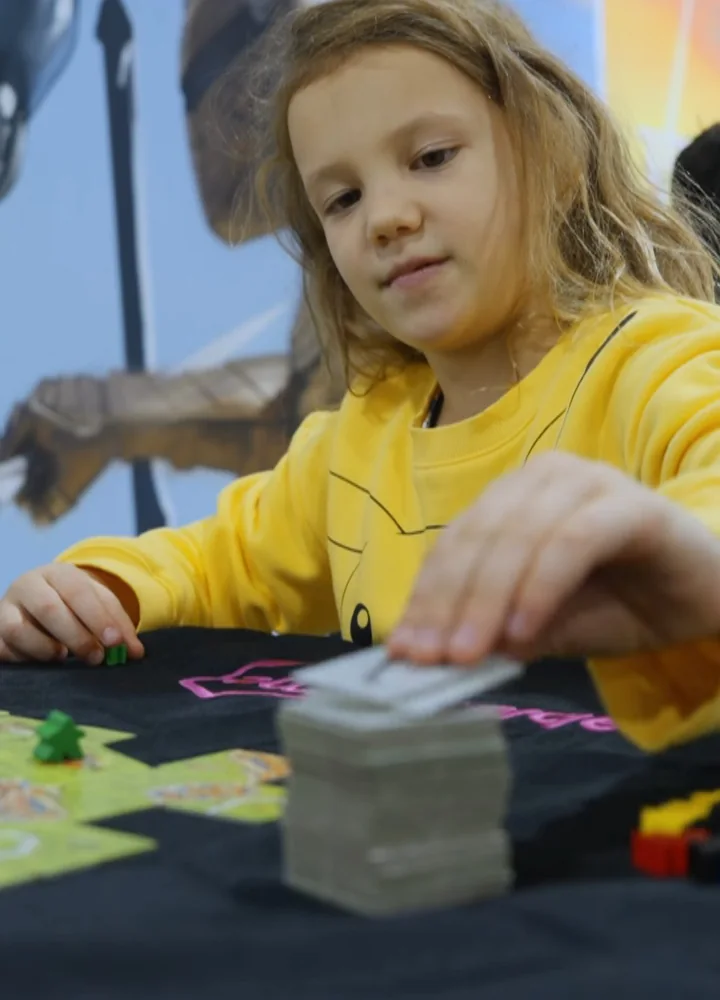 A young player placing a tile in a board game at tabletop.me